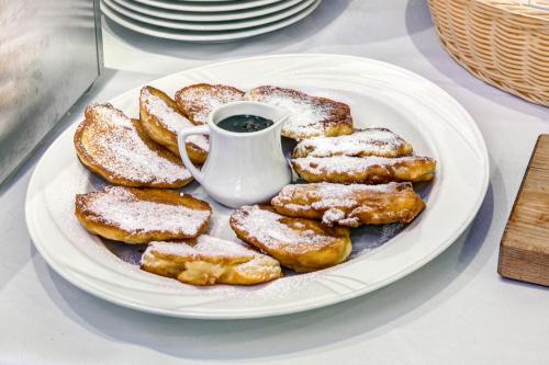 a plate of powdered donuts with a cup of coffee at Hotel i Restauracja Bona in Sanok