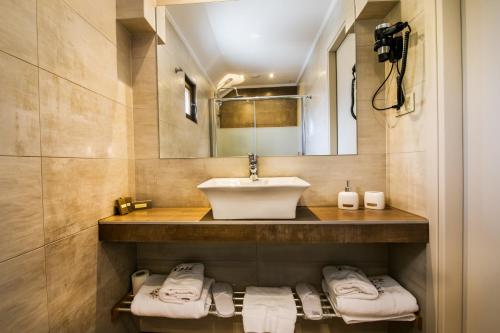 a bathroom with a sink and a mirror and towels at Ask Cozy Rooms in Thessaloniki