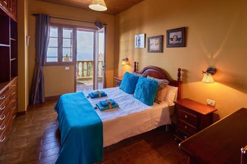 a bedroom with a bed with blue sheets and a window at Casa Mami Yaya in Firgas