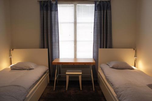 two beds in a room with a table and a window at B&B Lapväärtti in Lapväärtti