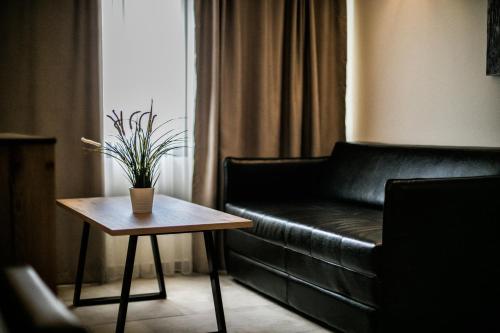 a living room with a black leather couch and a table at Ask Cozy Rooms in Thessaloniki