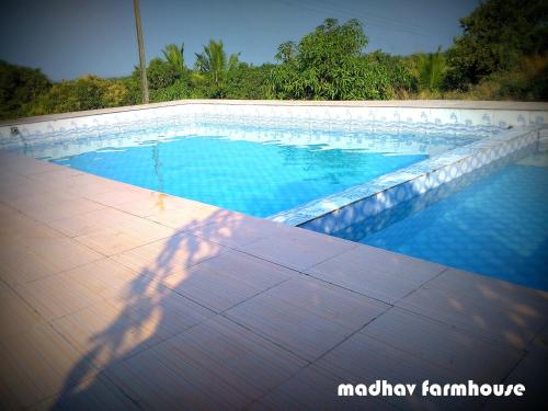 a shadow of a person standing next to a swimming pool at Madhav Farmhouse in Sasan Gir