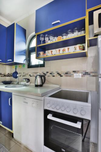 a kitchen with blue cabinets and a white stove top oven at Apartments Holiday Lux in Sutomore