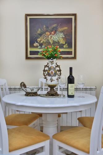 a white table with a vase and a bottle of wine at Apartments Holiday Lux in Sutomore