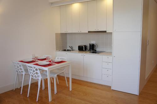 a white kitchen with a white table and chairs at Alfandega Apartments in Porto