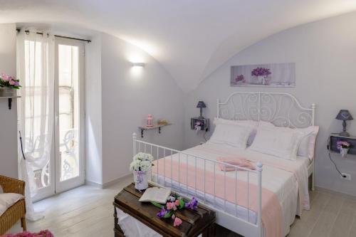 Un dormitorio con una cama rosa y blanca y una mesa en La Casa di Anetì, en Dolceacqua