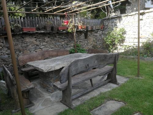 a wooden table and bench in a garden at Слънчевата къща in Kovachevitsa