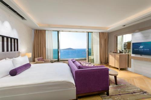 a bedroom with a large bed and a purple couch at Sirene Luxury Hotel Bodrum in Yalıkavak