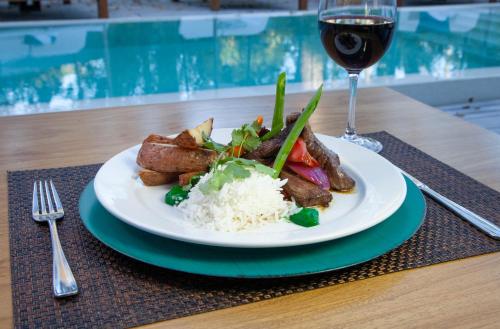 a plate of food with rice and a glass of wine at AWA Boutique + Design Hotel in Punta del Este