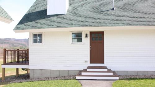 a small white house with a brown door at Owl's Nest Resort in Thornton