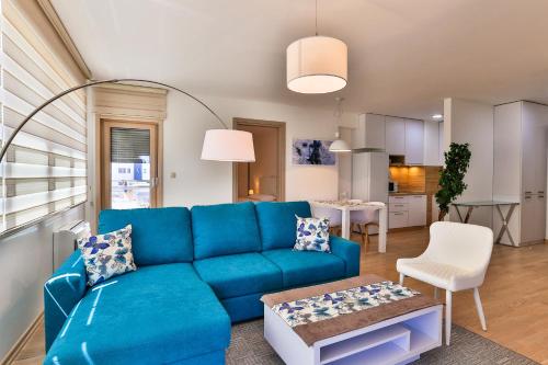 a living room with a blue couch and a kitchen at Gufo Apart in Budva