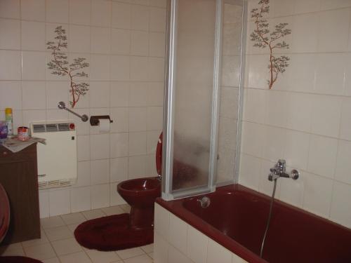 y baño con aseo rojo y bañera. en Ferienwohnung Lindlar, en Lindlar