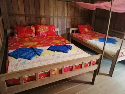 2 camas en una habitación con paredes de madera en Bee Bee's Chalets home stay and trekking, en Banlung