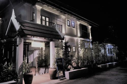 a building with potted plants in front of it at night at Moonlight Champa Riverview in Luang Prabang
