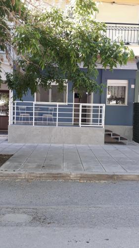 a blue building with a white fence in front of it at Elena Rooms-Apartments -B in Asprovalta