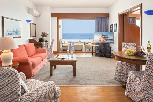 a living room with a orange couch and a tv at Elounda Beach Hotel & Villas, a Member of the Leading Hotels of the World in Elounda