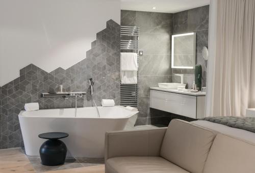 a bathroom with a tub and a couch and a sink at Petit Hôtel Confidentiel in Chambéry