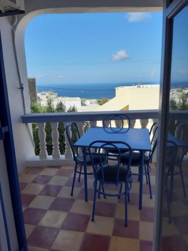 a table and chairs on a balcony with the ocean at Katerina Kafieri Apartments in Firostefani