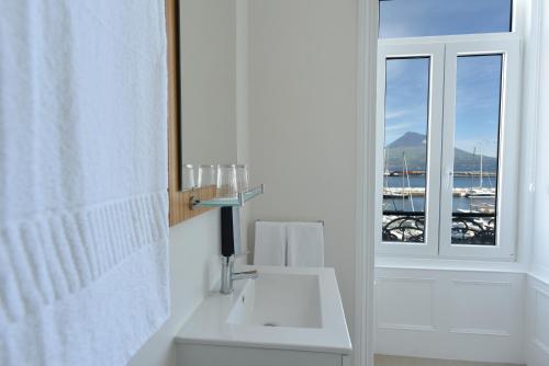 une salle de bain blanche avec un lavabo et une fenêtre dans l'établissement Internacional Azores Boutique, à Horta