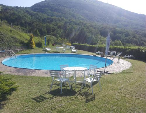 a pool with chairs and a table in the grass at apartment details Granaio in Pulicciano
