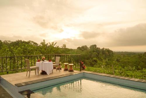 a table and chairs on a deck next to a pool at Dukuh Baturan Villa in Jatiluwih