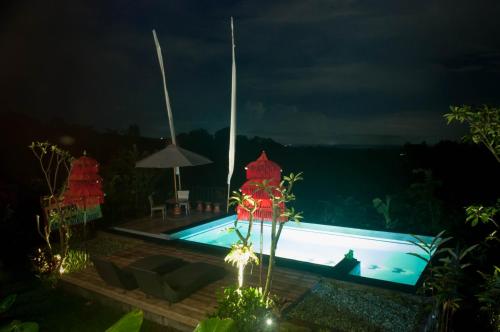 a swimming pool at night with lights at Dukuh Baturan Villa in Jatiluwih