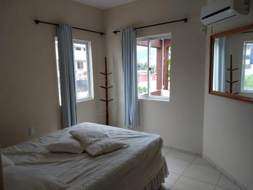 uma cama num quarto com 2 janelas em Residencial Melfi 3 Ap.8 Fundos em Bombinhas
