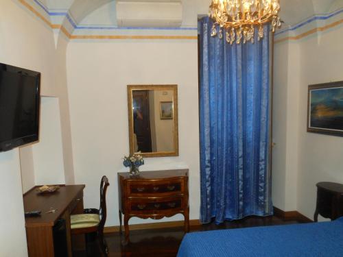 タルクイーニアにあるPalazzo Rosatiのベッドルーム(青いカーテン、ドレッサー、鏡付)