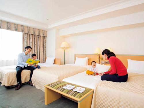 una familia sentada en las camas en una habitación de hotel en Keio Plaza Hotel Hachioji, en Hachioji