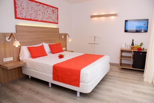 Un dormitorio con una cama grande con almohadas rojas. en Cala Llenya Resort Ibiza, en Cala Llenya