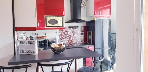 une cuisine avec un comptoir noir et des armoires rouges dans l'établissement Chez Damien, à Colmar