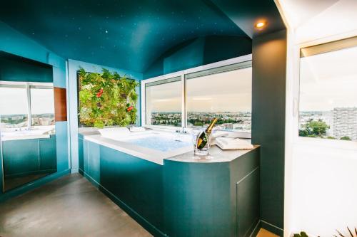 uma casa de banho azul com uma banheira e uma grande janela em Parenthèse Concept Room em Toulouse