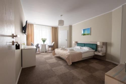 a bedroom with a bed and a desk and a table at Biały Gościniec in Ciechanów