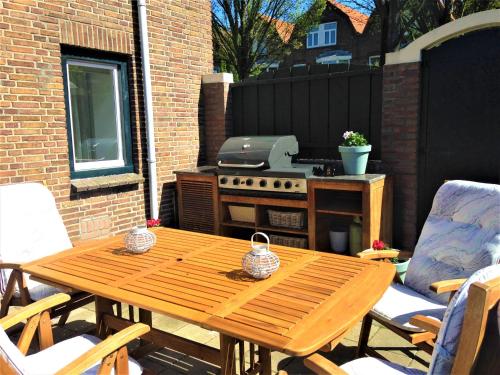 a wooden table and chairs on a patio with a grill at Westerschelde B&B in Vlissingen