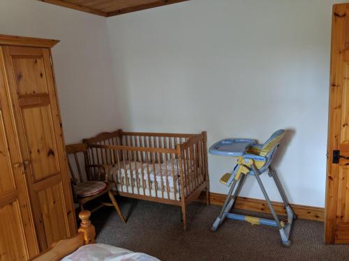 a room with a crib and a table and a chair at The Rathbarn in Newry