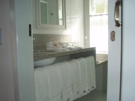 a bathroom with white towels and a sink and a mirror at Pousada Vale Dos Figos in Urussanga