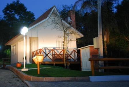 a small white house with a light on the grass at Pousada Vale Dos Figos in Urussanga