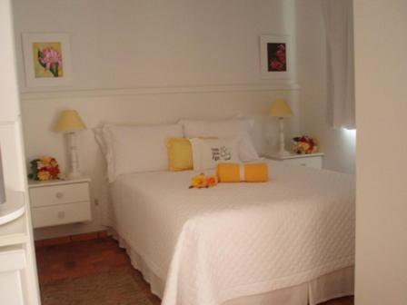 a white bedroom with a white bed with yellow pillows at Pousada Vale Dos Figos in Urussanga