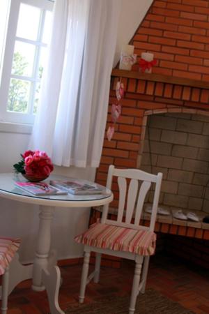 a table and a chair and a brick fireplace at Pousada Vale Dos Figos in Urussanga