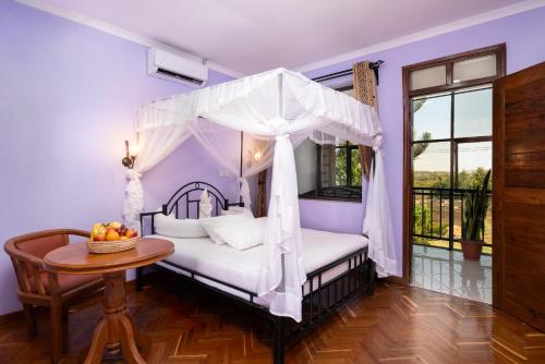 a bedroom with a canopy bed and a table at Mrimba Palm Hotel in Arusha