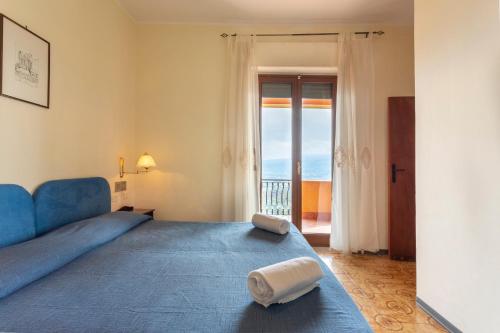 1 dormitorio con cama azul y vistas al océano en Hotel Sole Castello, en Taormina