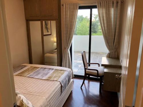 Un dormitorio con una cama y un escritorio y una ventana. en 500Mbps Wi-Fi 2 Largest 2 BDRM Condo in Grand Residences, en Cebú