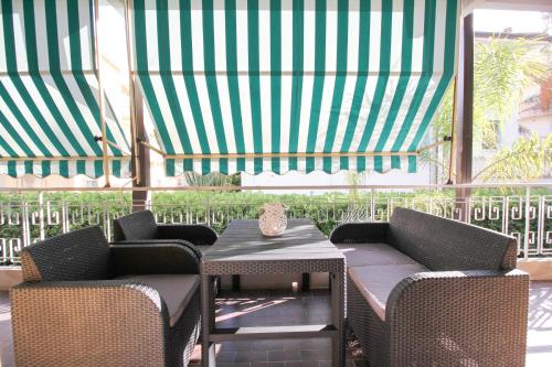 a patio with two chairs and a table and a green canopy at Parrots & Palms in Bordighera