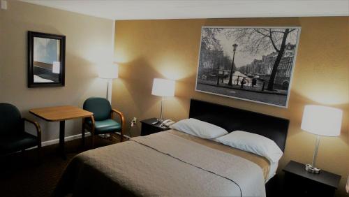 a hotel room with a bed and a picture on the wall at Attican Motel - Attica - Batavia - Warsaw - Darien Lake in Attica