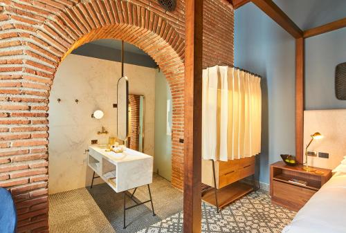 a room with a brick wall and a bathroom with a sink at Hotel Boutique Casona del Colegio in Cartagena de Indias