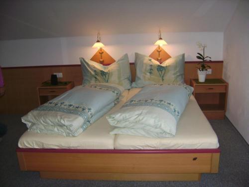 a bed with two pillows on it with two lights at Landhaus Trinker in Schladming