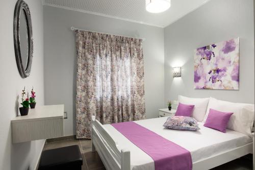 - une chambre avec un grand lit blanc et des oreillers violets dans l'établissement De plata apartments, à Sarti