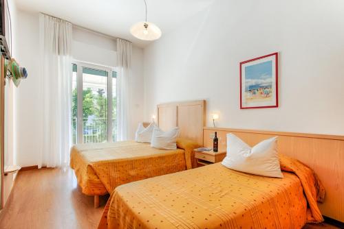 una camera d'albergo con due letti e una finestra di Hotel Venezia e la Villetta a Lido di Jesolo