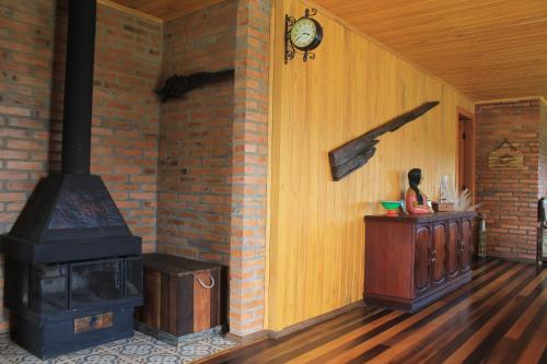 una habitación con estufa y una mujer sentada en una habitación en Casa da Montanha en Urubici
