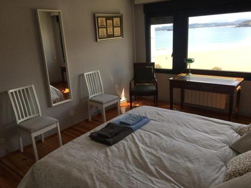a bedroom with a bed and two chairs and a piano at VISTAS AL MAR in Santander